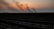 © Ubaidillah - Distant wildfire smoke obscures a setting sun over a field of dry crops