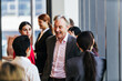 © artitwpd - Professionals networking and chatting in a bright office corridor during a business event.