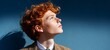 © iuricazac - Ginger-haired male in casual attire standing outdoors against blue background.