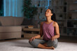 © Antonioguillem - Black woman is doing yoga breathing exercise in the night