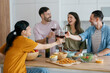 © Westend61 - Friends toasting with wine and enjoying dinner together at home