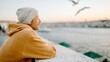 © Pinklife - A thoughtful man in a beanie gazes across the water during sunset, evoking feelings of introspection, serenity, and connection with nature.