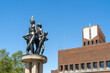 © Travel 'n' Lifestyle - View of bronze sculptures gleam under a clear blue sky, contrasting with the brick facade of Oslo city hall at Radhus Plass, capturing a unique urban moment, Oslo, Oslo, Norway.