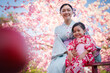 © geargodz - woman and child girl in yukata (kimono dress) on red bridge with sakura flower or cherry blossom blooming in garden
