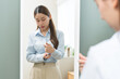 © KMPZZZ - Get dress, asian young woman, businesswoman standing, hand buttoning up shirt formal, female getting dressed, ready before go to work looking reflection the mirror in bedroom in the morning at home.