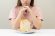 © KMPZZZ - Gluten allergy asian young woman expression face, looking bread refusing to eat on plate in breakfast food meal, girl having a stomach ache. Gluten intolerant and Gluten free, diet getting fat concept