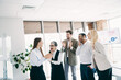 © deagreez - Group of coworkers celebrating and sharing enthusiasm in a bright modern office setting