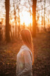 © krugli - Young Woman Standing in Spring Forest at Sunset