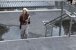 © wavebreak3 - Female student walking up tiled steps holding folders, wearing knit beanie, plaid shirt, copy space