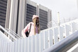 © wavebreak3 - African American teen climbing stairs at plaza wearing pink hoodie backpack headset, copy space