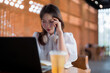 © Pichsakul - Asian adult woman intensely concentrates using laptop computer working studying problem solving remote in modern cafe environment