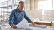 © Vasiliy - Senior male architect reviewing blueprints at a construction site office. Professional engineer planning building project