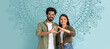 © Prostock-studio - A couple stands together, forming a heart shape with their hands. They smile while posing in front of a decorative, patterned wall. This collage captures their joyful moment.