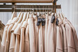 © ADDICTIVE STOCK - Beige coats on hangers showcased in clothing store rack