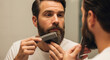 © Guilherme - Handsome man combing his beard in the mirror