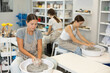 © JackF - Three young women sits near potter wheel and makes clay crafts, makes vase plate, works in company of like-minded craftsmen. Handmade art, hobbies and creativity.