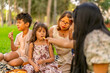 © Guillermo Spelucin - Multigenerational family enjoying picnic snacks in park
