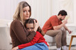 © New Africa - Alcohol addiction. Drunk man smoking on sofa at home, focus on his scared wife and daughter