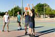 © AntonioDiaz - Hispanic men playing basketball on an outdoor court, actively moving and shooting during a game