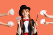 © Pixel-Shot - Young magician and hands with playing cards on orange background