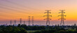 © ABCDstock - High voltage electricity pylons and transmission lines at sunset. Power grid and energy infrastructure industry concept.
