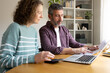 © Daniel - Couple planning family budget discussing finances using laptop