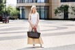 © Anna Zhukkova - Full length portrait stylish young woman standing outdoors in city near modern building. Female wearing beige sleeveless maxi dress, headscarf, flat shoes, holding Tote handbag, summer urban fashion