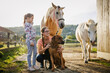 © encierro - Portrait of woman and her daughter with dog and horses on family ranch at sunset. Rural lifestyle with pets and animals. Happy moment together