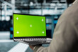 © DC Studio - Close up of technician using green screen laptop in high tech data center to check for server performance issues. Server hub workplace employee fixes errors slowing down hardware using mockup notebook
