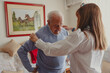 © Luis - Daughter assisting senior man with dressing at home