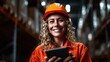 © svastix - A cheerful woman wearing an orange safety vest and helmet holds a tablet, representing empowerment and the importance of safety in industrial environments in a vibrant setting.