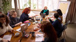 © master1305 - Women business team working together at large wooden table. Concept of inclusive workplace culture, leadership guidance, strategic planning session, corporate collaboration, professional development.