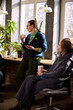 © master1305 - Senior woman leading informal office discussion with coffee in hand. Concept of mentoring leadership, supportive team culture, workplace communication, collaborative planning session.