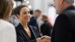 © Mary - Businesswoman smiling while shaking hands with a man indoors