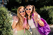 © deagreez - Fun loving two friends pose with sunglasses backpacks ready for summer city adventure and joyful journey together