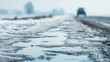 © Bonsales - Melting snow and ice on a rural road, creating puddles reflecting the sky with a car driving away