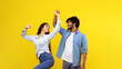 © Prostock-studio - A couple enjoys dancing together in a studio. They share smiles and laughter while moving to music. The bright yellow background adds to the joyful atmosphere of the moment.