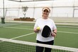 © Angelov - mature woman playing padel on outdoor court.