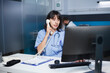 © DC Studio - In the hospital office, a medical practitioner answers phones and schedules appointments. In a modern clinic, a health care provider sits at a desk, using a landline and staring at a monitor.