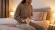 © praewpailyn - Uterine fibroid pelvic pain concept uterus women health gynecology medical awareness female discomfort on bed warm light bedroom interior