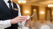 © sitiprapti - Closeup of a waiter or waitress in formal uniform holding a notepad and pen while taking an order at a restaurant or event venue with warm lighting and elegant decor in the background