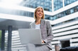 © Westend61 - Smiling young businesswoman using laptop in the city