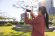 © leungchopan - Woman using smartphone to take photo in park