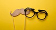 © Shakir - Wooden mustache and black glasses on sticks against yellow background