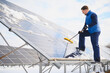 © Serhii - Worker cleaning snow from solar panels in winter