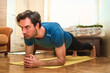 © Teodor Lazarev - Determined adult man holding plank pose on a yoga mat during a focused core workout at home, building strength and improving fitness