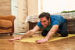 © Teodor Lazarev - Man practicing yoga at home, stretching on a mat for fitness and mental well-being, focusing on inner peace and physical health in a calm environment