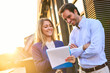 © Teodor Lazarev - Business colleagues collaborating outdoors, discussing paperwork and smiling, enjoying successful teamwork and corporate partnership in natural light