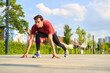 © Teodor Lazarev - Athletic man adopting a sprinter's start position on a paved surface, preparing to run, focused on his fitness and training routine in an outdoor urban setting