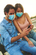 © Teodor Lazarev - Couple wearing protective medical masks and looking at smartphone screen together, sharing content and connecting online during pandemic and lockdown